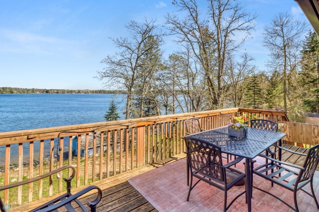 deck with a water view and outdoor dining area