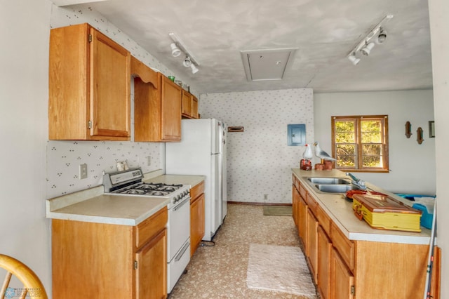 kitchen with white appliances, a sink, rail lighting, light countertops, and wallpapered walls