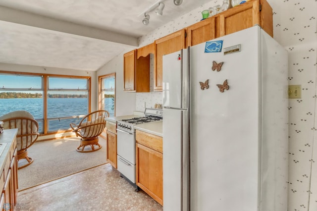kitchen with white appliances, plenty of natural light, lofted ceiling, a water view, and light countertops