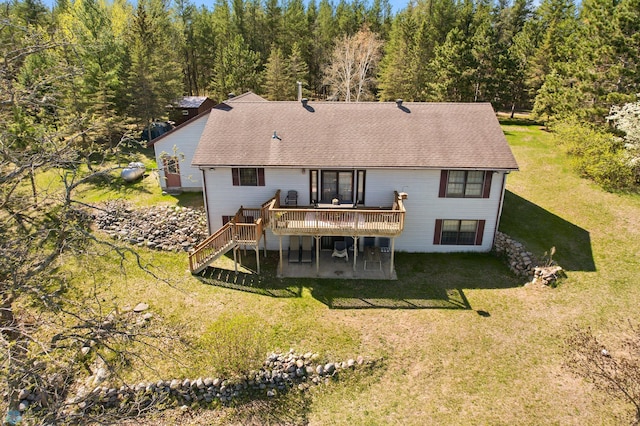 rear view of property with a wooden deck, stairway, a lawn, and a shingled roof