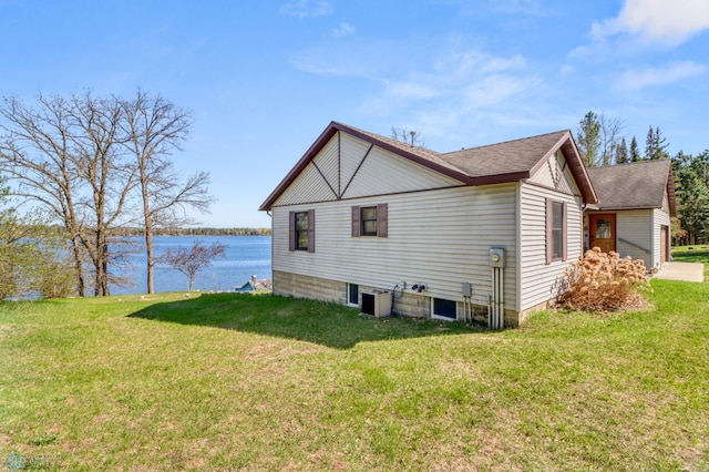 view of side of home with a water view, a yard, roof with shingles, and central AC