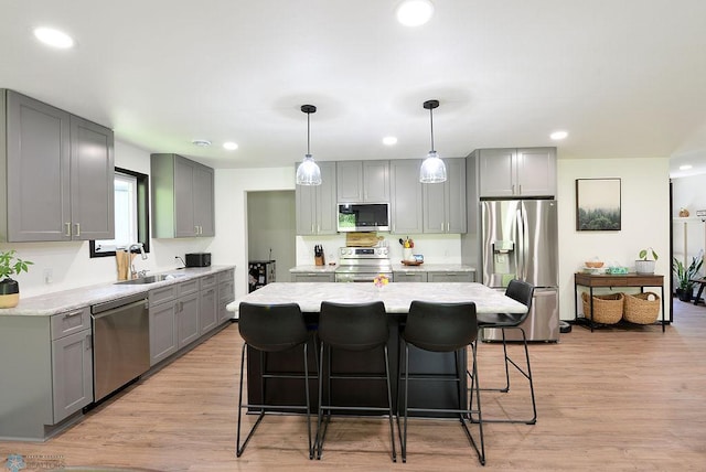 14840 Eaglewood Dr, Burlington Twp, MN 56501 - kitchen featuring stainless steel appliances, gray cabinetry, a breakfast bar, light wood-style flooring, and a center island