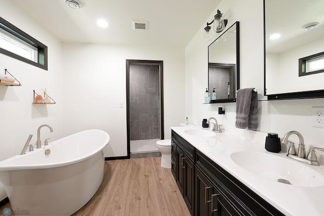 14840 Eaglewood Dr, Burlington Twp, MN 56501 - bathroom featuring wood finished floors, a shower stall, a freestanding bath, double vanity, and toilet