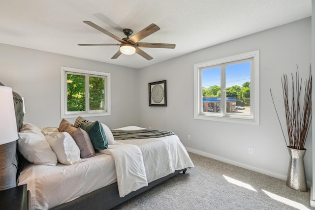 carpeted bedroom featuring multiple windows, baseboards, and ceiling fan