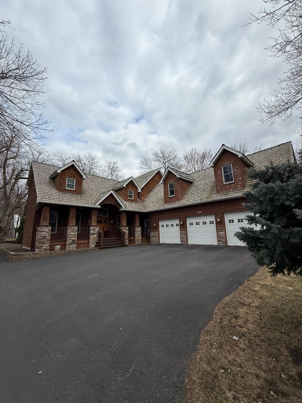 view of front of property with stone siding, covered porch, driveway, and a garage