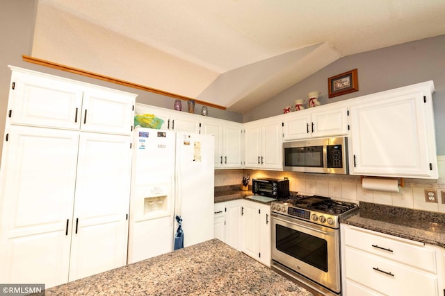 155 Palomino Ln, Lino Lakes, MN 55014 - kitchen featuring stainless steel appliances, tasteful backsplash, vaulted ceiling, dark stone counters, and white cabinetry