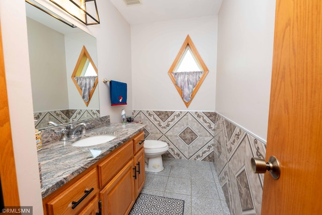 155 Palomino Ln, Lino Lakes, MN 55014 - bathroom featuring toilet, vanity, a wainscoted wall, tile walls, and tile patterned flooring