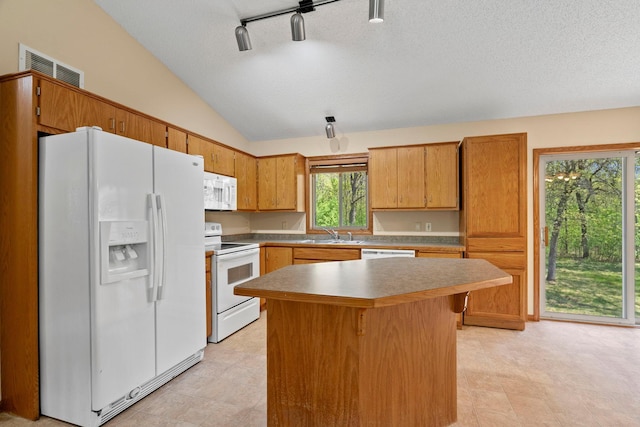 kitchen featuring white appliances, vaulted ceiling, a sink, a center island, and a textured ceiling