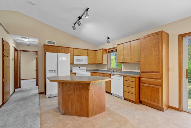 kitchen featuring white appliances, lofted ceiling, a kitchen island, a sink, and a kitchen bar