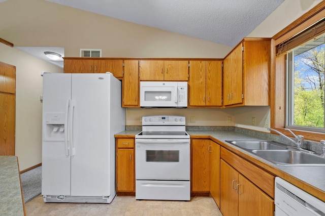 kitchen featuring white appliances, vaulted ceiling, a sink, a textured ceiling, and brown cabinetry