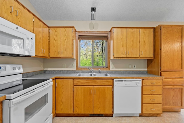 kitchen featuring white appliances, a sink, and a textured ceiling
