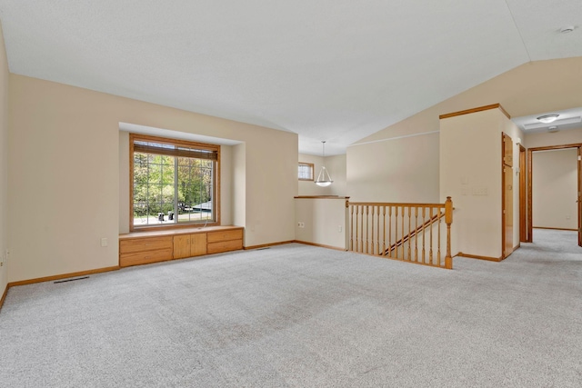 empty room featuring light colored carpet, lofted ceiling, and baseboards