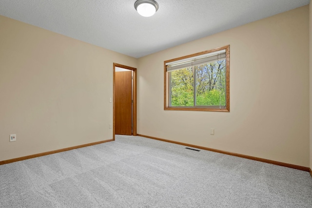 unfurnished room with carpet floors, baseboards, and a textured ceiling
