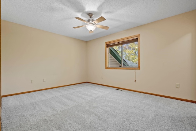 carpeted empty room with baseboards, a ceiling fan, and a textured ceiling