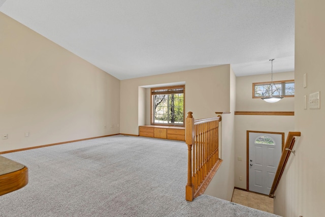 entrance foyer with light colored carpet, baseboards, and a chandelier