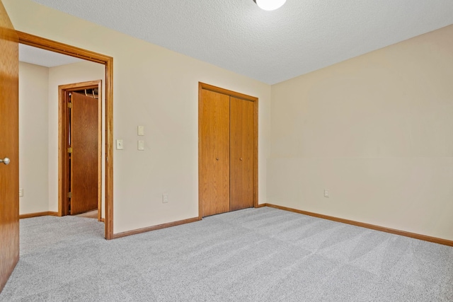 unfurnished bedroom featuring carpet floors, a closet, baseboards, and a textured ceiling