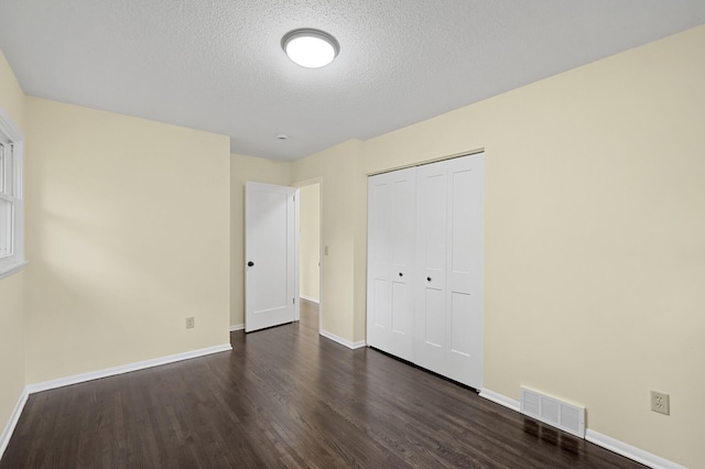2756 Sunset Ln, Burnsville, MN 55337 - unfurnished bedroom with dark wood-type flooring, baseboards, a textured ceiling, and a closet