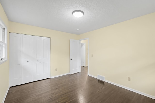 2756 Sunset Ln, Burnsville, MN 55337 - unfurnished bedroom featuring dark wood-style flooring, baseboards, a textured ceiling, and a closet