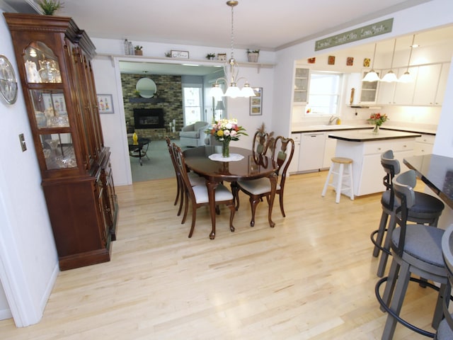 dining area with a large fireplace and light wood-style flooring