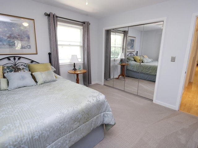 carpeted bedroom with a closet and baseboards
