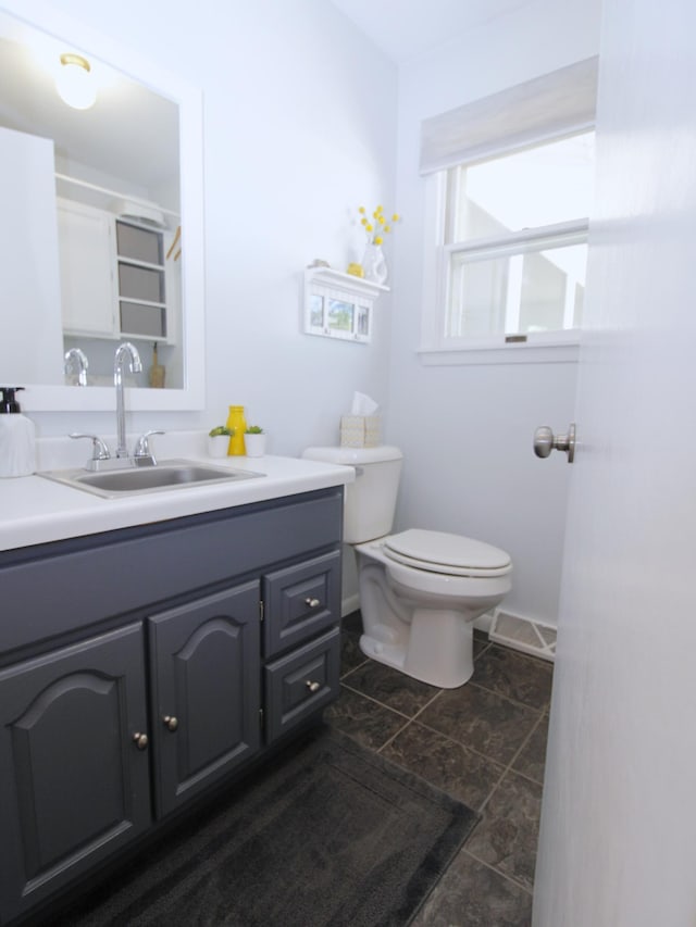 bathroom with toilet, vanity, and baseboards