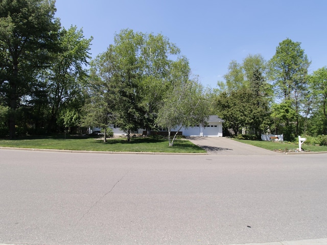 obstructed view of property featuring a garage, a front lawn, and driveway