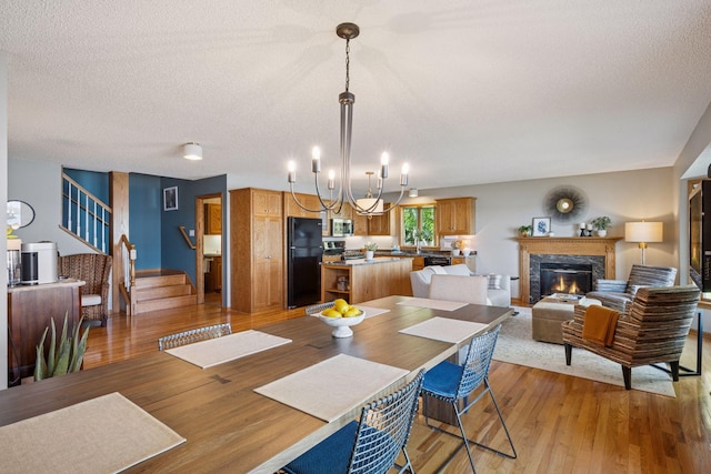 10547 Hollister Ave NW, Maple Lake, MN 55358 - dining room with stairs, light wood-style floors, a textured ceiling, a high end fireplace, and a chandelier