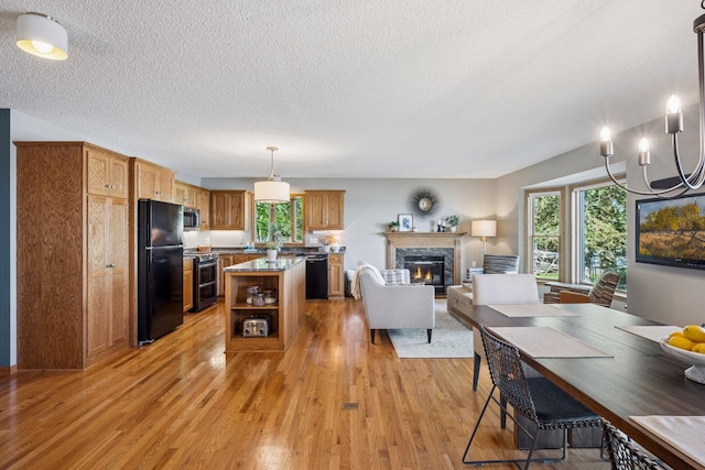 10547 Hollister Ave NW, Maple Lake, MN 55358 - kitchen featuring black appliances, healthy amount of natural light, light wood-type flooring, a textured ceiling, and a warm lit fireplace