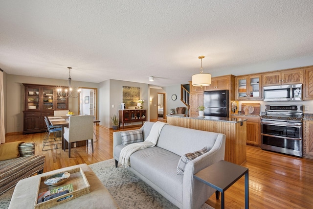10547 Hollister Ave NW, Maple Lake, MN 55358 - living room with a chandelier, light wood-style floors, a textured ceiling, and baseboards