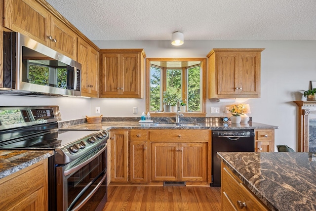 10547 Hollister Ave NW, Maple Lake, MN 55358 - kitchen with stainless steel appliances, a sink, a textured ceiling, light wood finished floors, and healthy amount of natural light