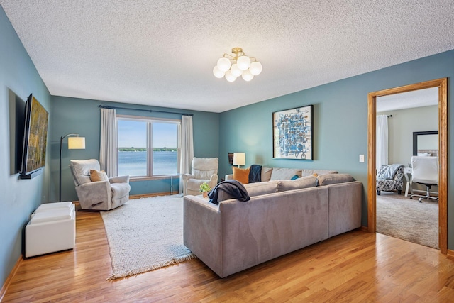 10547 Hollister Ave NW, Maple Lake, MN 55358 - living area with a chandelier, light wood-style flooring, a textured ceiling, baseboards, and a water view