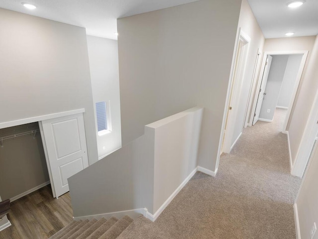 hall featuring an upstairs landing, baseboards, carpet flooring, and recessed lighting