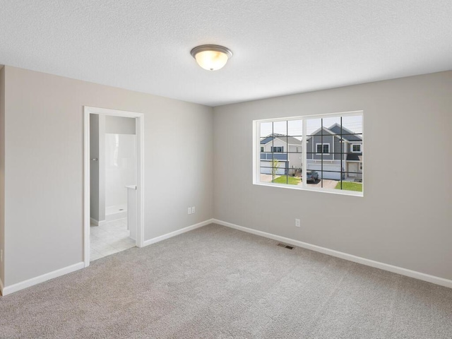 unfurnished room featuring carpet floors, baseboards, and a textured ceiling