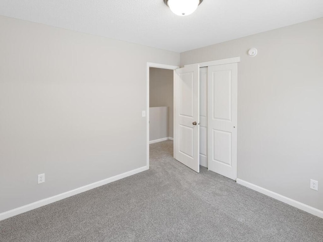 unfurnished bedroom featuring carpet flooring, baseboards, and a closet