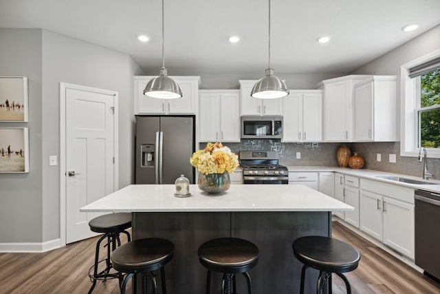 9587 Jada Way, Elko New Market, MN 55020 - kitchen with appliances with stainless steel finishes, a sink, wood finished floors, white cabinetry, and decorative backsplash
