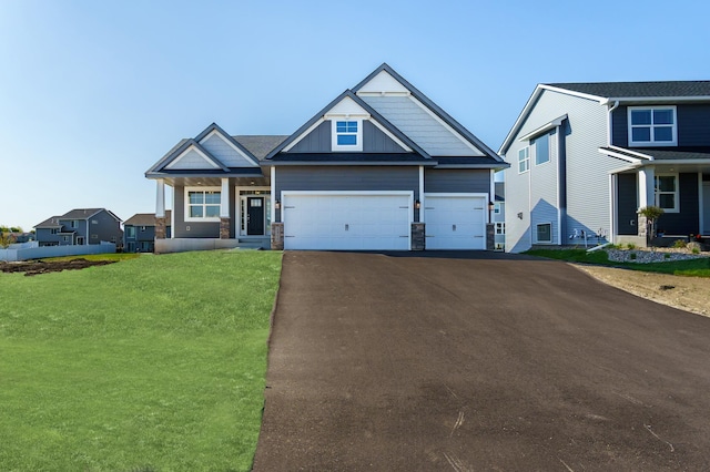 craftsman-style home with driveway, a front lawn, stone siding, an attached garage, and board and batten siding