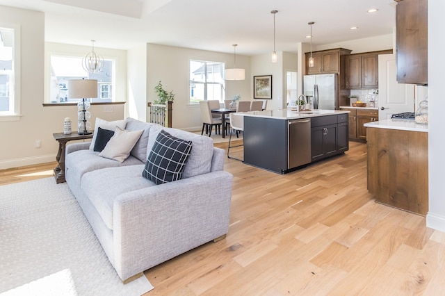 living area with light wood finished floors, recessed lighting, baseboards, and a chandelier