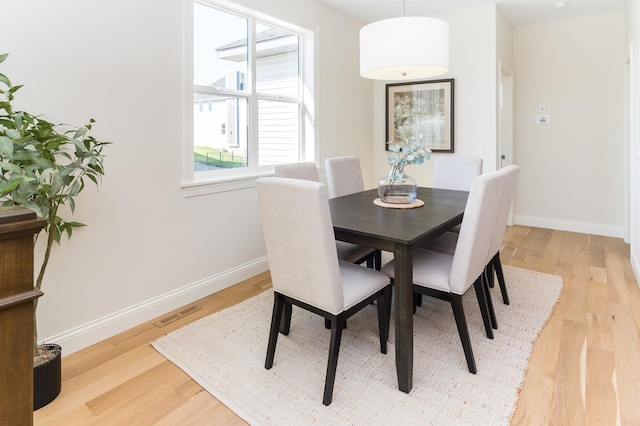 dining area featuring light wood finished floors and baseboards