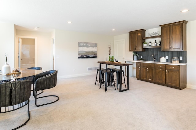 kitchen featuring a sink, open shelves, light colored carpet, light countertops, and recessed lighting