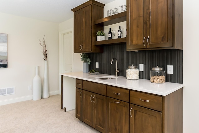 bar area featuring a sink, light colored carpet, and baseboards
