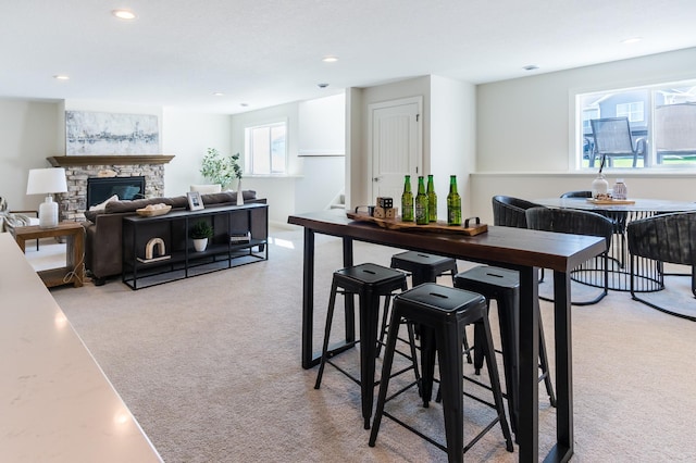 carpeted dining area with recessed lighting and a stone fireplace