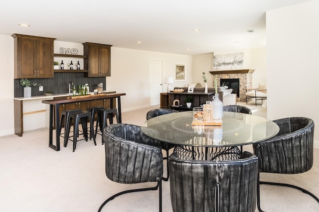 dining area featuring light carpet, a fireplace, baseboards, recessed lighting, and wet bar