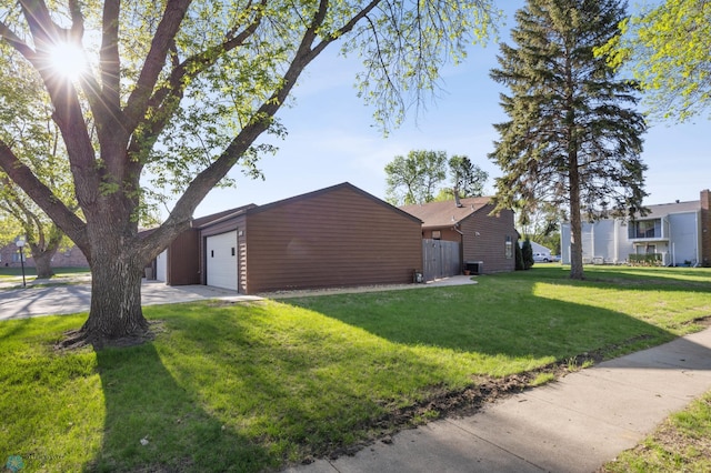 view of side of property featuring an attached garage, a lawn, and concrete driveway