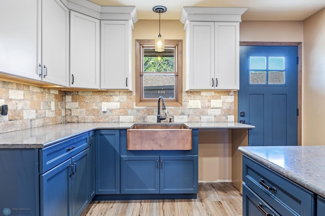 kitchen with blue cabinetry, a sink, and white cabinetry