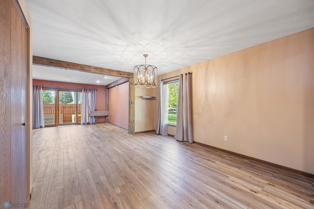 empty room with healthy amount of natural light, light wood-style flooring, a chandelier, and beamed ceiling