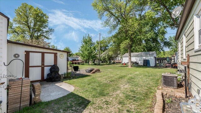 335 Cossairt Ave W, Eden Valley, MN 55329 - view of grassy yard with central AC unit, a storage unit, and an outbuilding