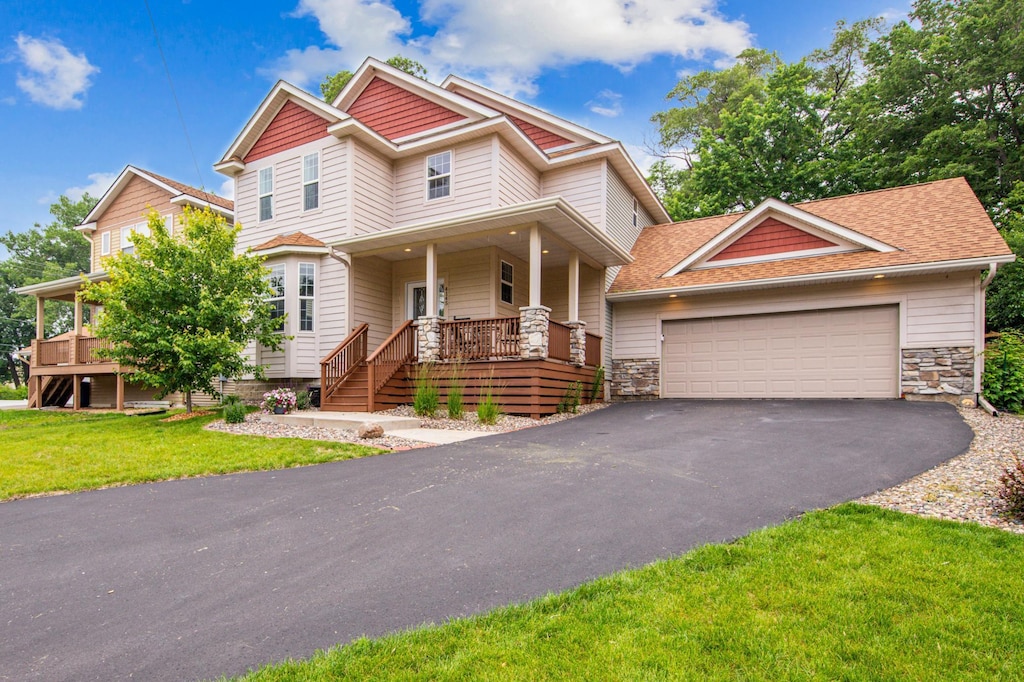 4145 Halifax Ave N, Robbinsdale, MN 55422 - craftsman inspired home featuring a porch, driveway, a front yard, stone siding, and a garage