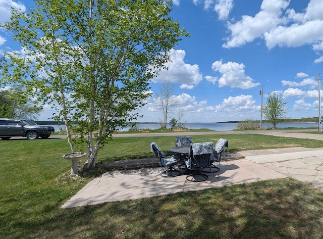view of grassy yard featuring a patio and a water view