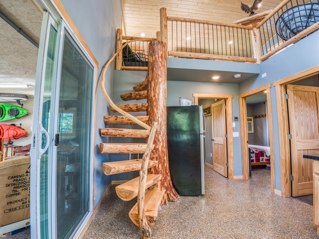 stairway featuring baseboards, a high ceiling, and speckle patterned floor