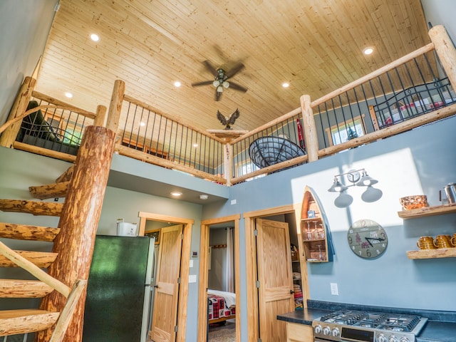 kitchen with a high ceiling, wooden ceiling, gas stove, a ceiling fan, and dark countertops
